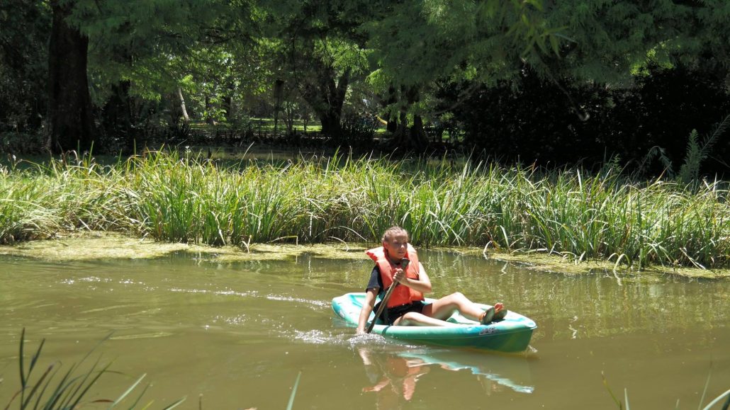 A camper paddling a kayak on the pond