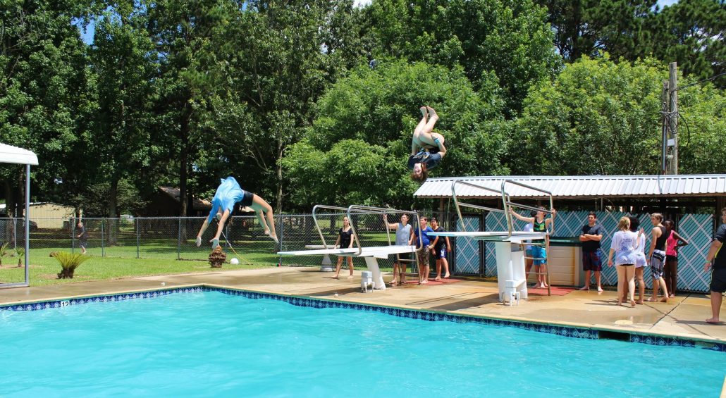 Campers jumping off the diving boards at the pool